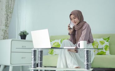 asian woman in hijab working from home talking on cell phone