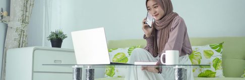 asian woman in hijab working from home talking on cell phone