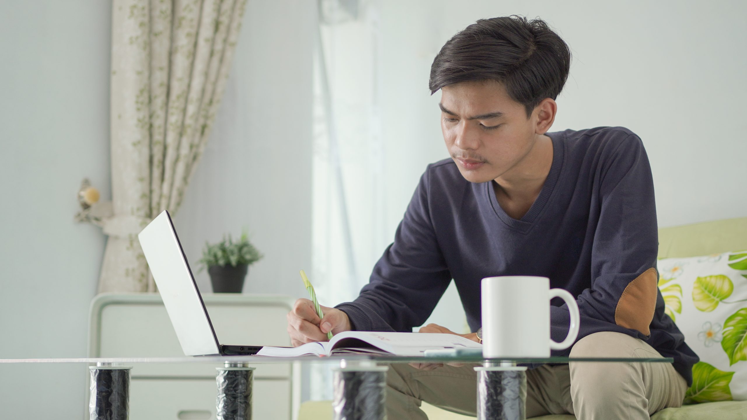 young asian man working from home taking notes