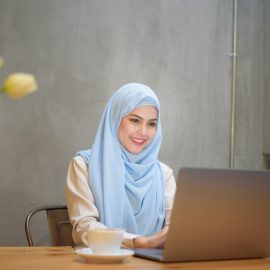 Muslim woman with hijab is working with laptop computer in coffee shop